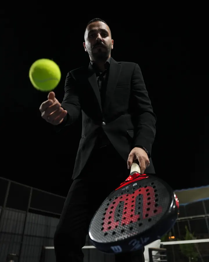 A player in a black suit tossing a ball at night