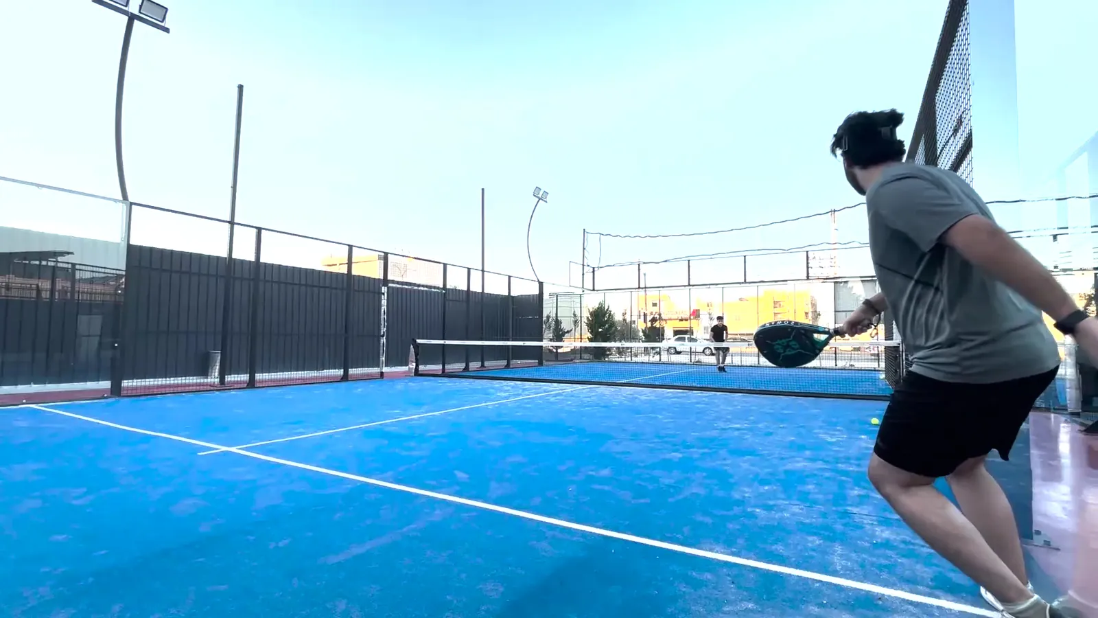 A player mid swing on a Padel X court at dusk
